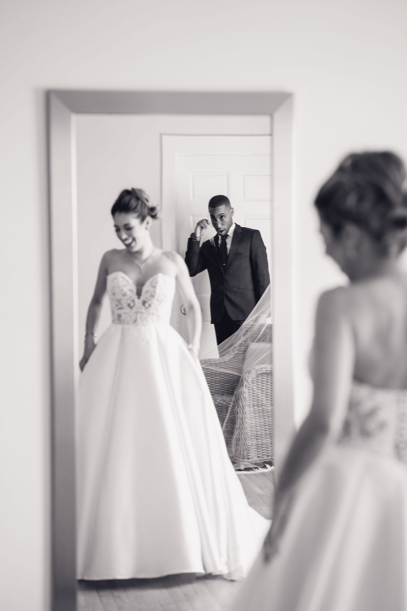 Bride in lace wedding gown reflected in mirror with the her man of honor seeing her dressed for the first time in the getting-ready suite at Alhambra Hall Charleston