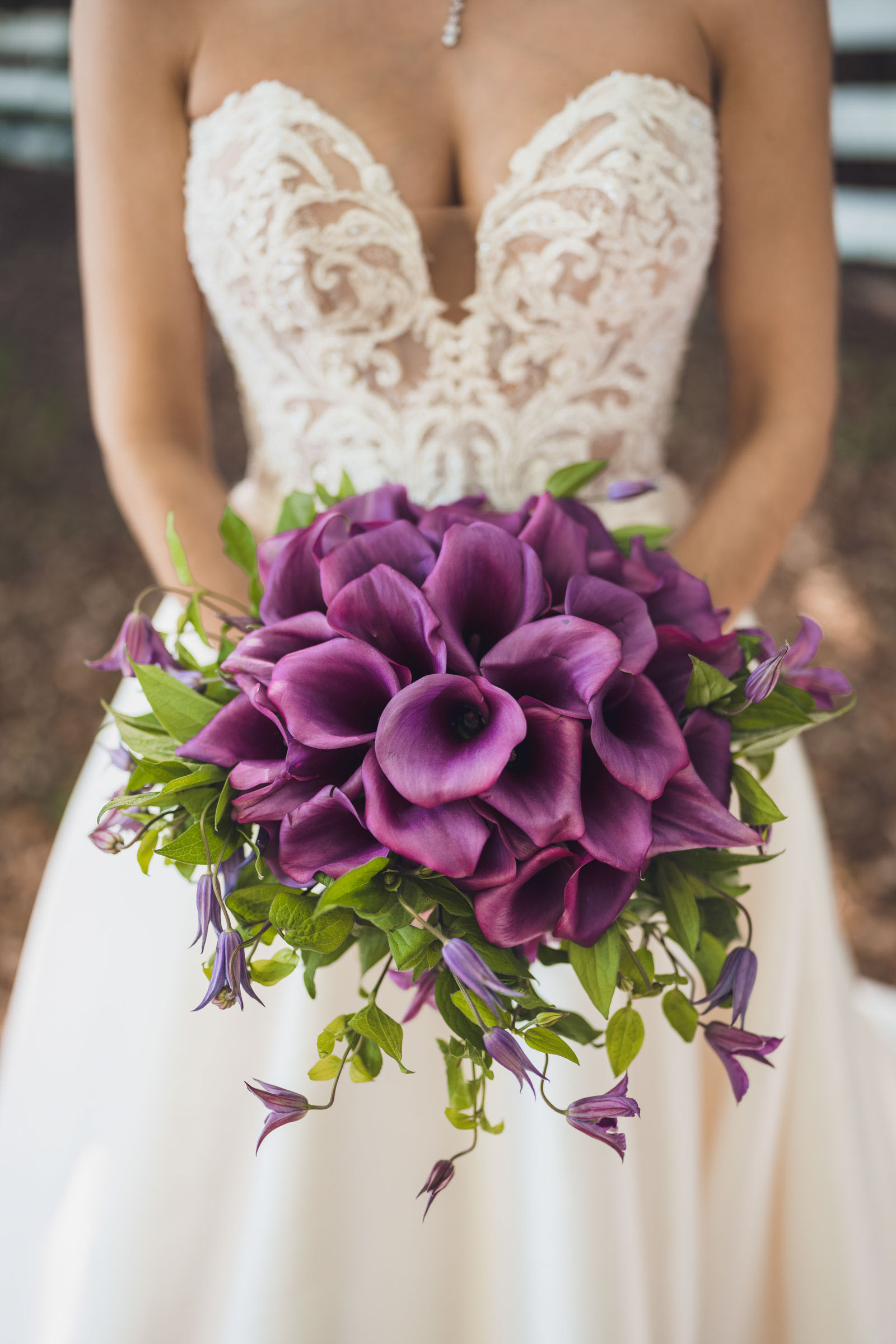 Close up of bride holding purple calla lily bouquet against lace wedding dress at Alhambra Hall