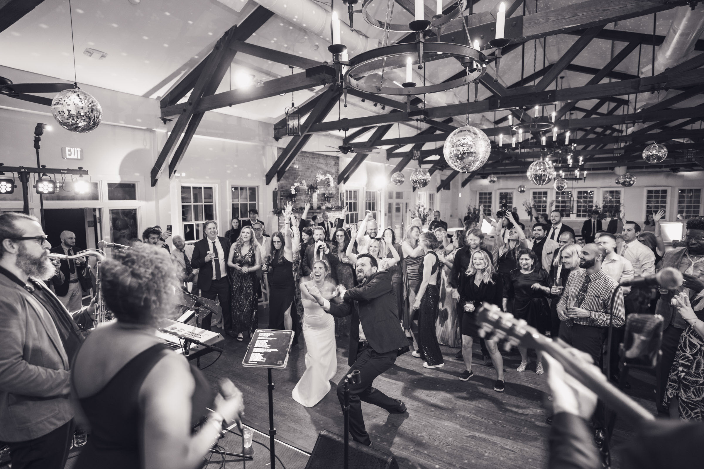 Crowded dance floor with bride and groom dancing energetically in front of live band at Alhambra Hall