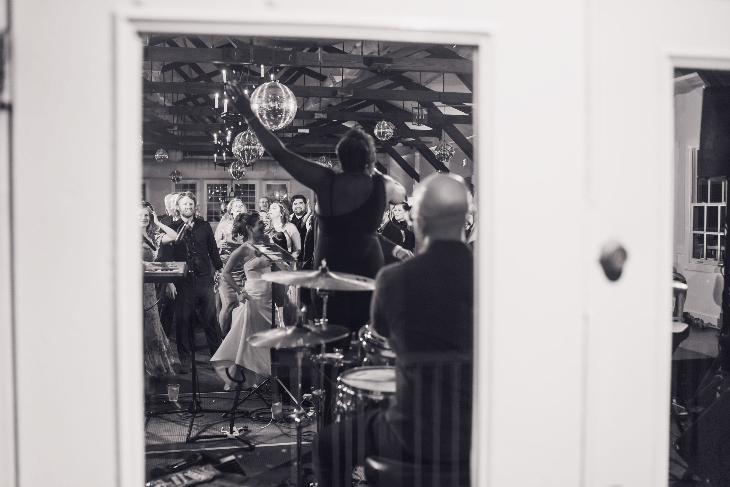 View of reception dance floor through window with drummer and guests dancing at Alhambra Hall