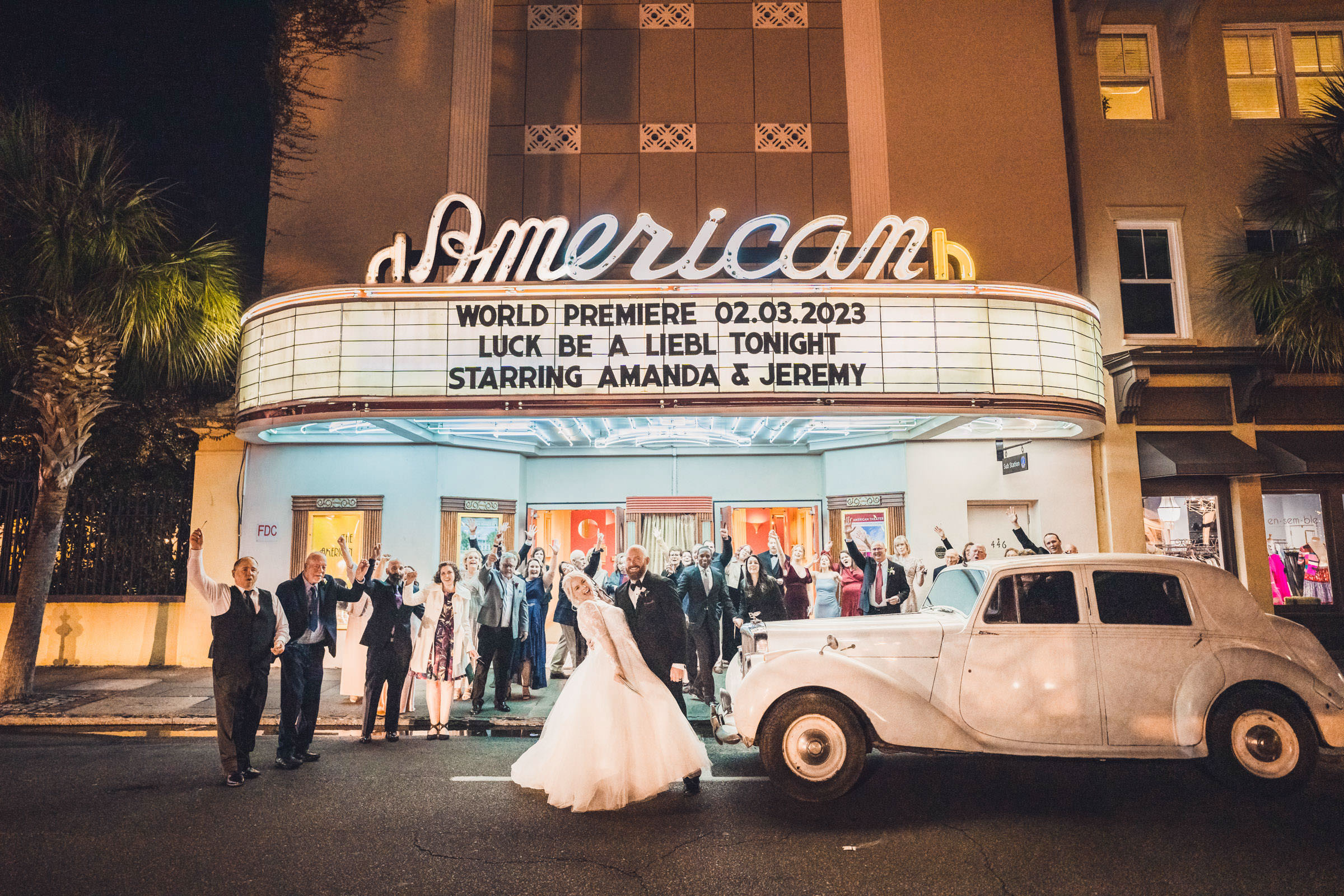 American Theater Wedding Marquee Newlyweds and wedding guests celebrating beneath the illuminated American Theater marquee with a vintage car