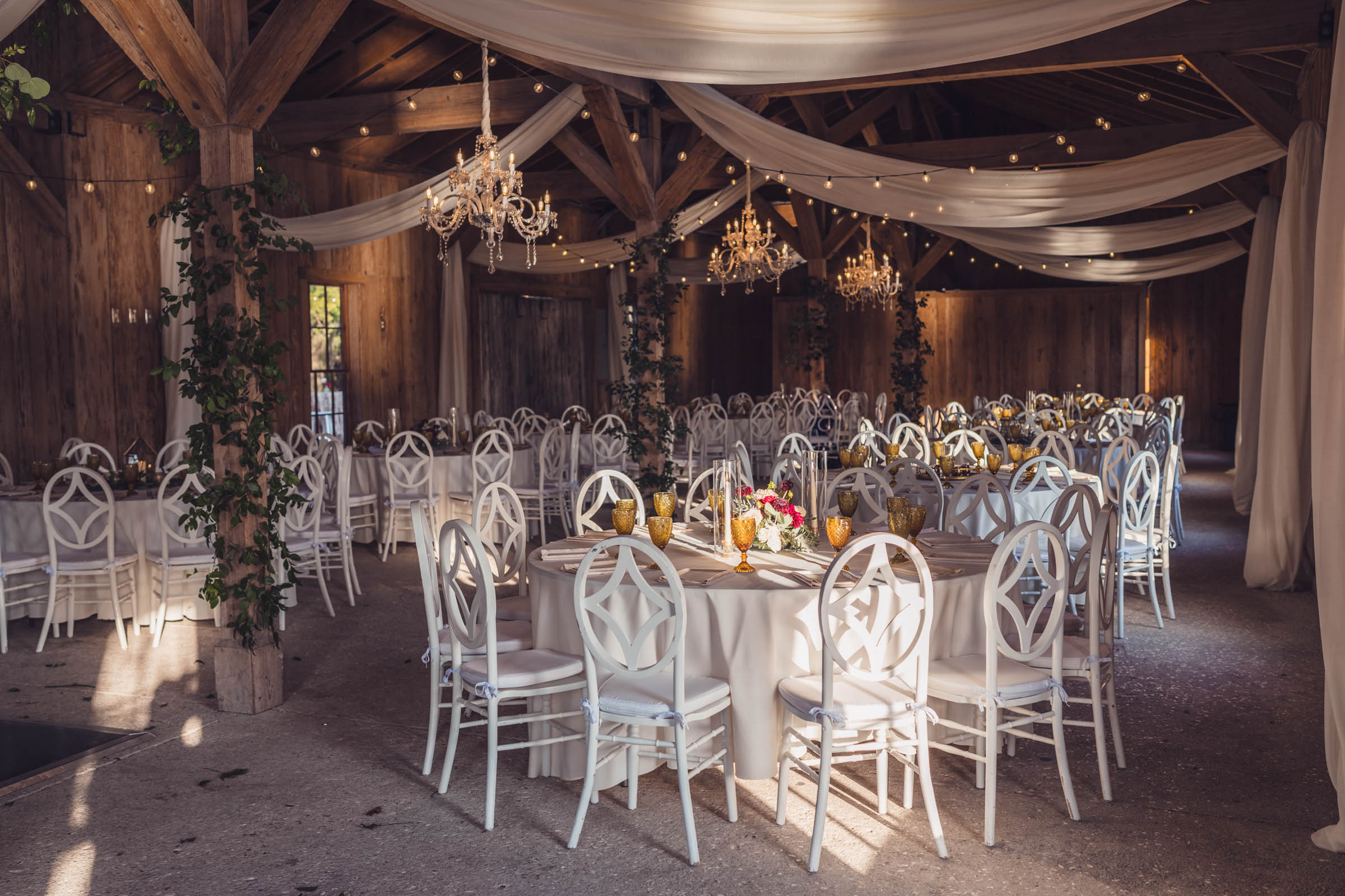 Boone Hall Cotton Dock Reception Wedding reception inside the Cotton Dock with chandeliers, white draping and tables prepared for guests