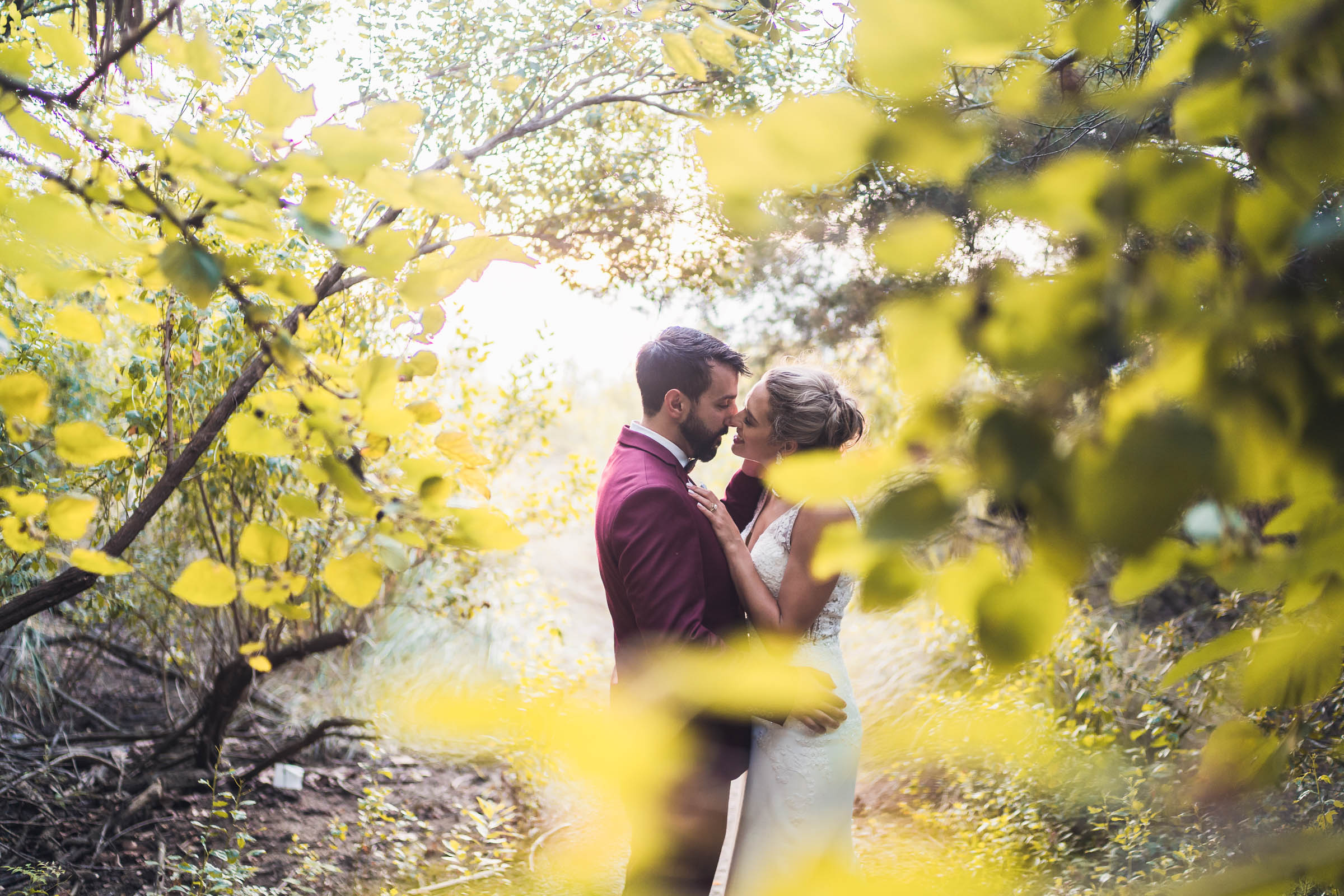 Bride and groom kiss among trees and greenery on the grounds of Charleston Harbor Resort & Marina.