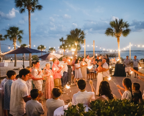 Wedding guests surround the newlyweds with sparklers during an outdoor waterfront reception at Charleston Harbor Resort & Marina.