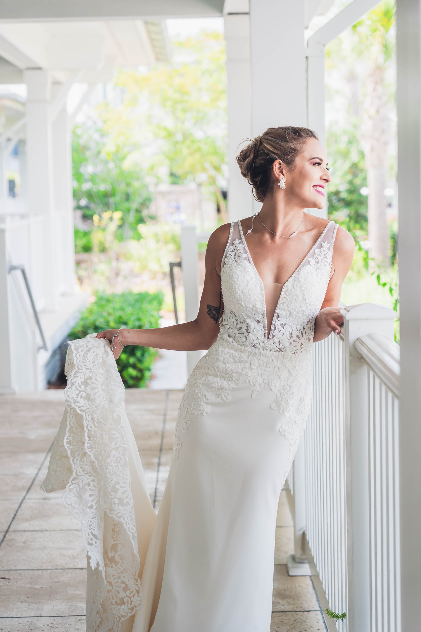 Bride in a lace wedding dress stands on a bright covered porch at Charleston Harbor Resort & Marina.