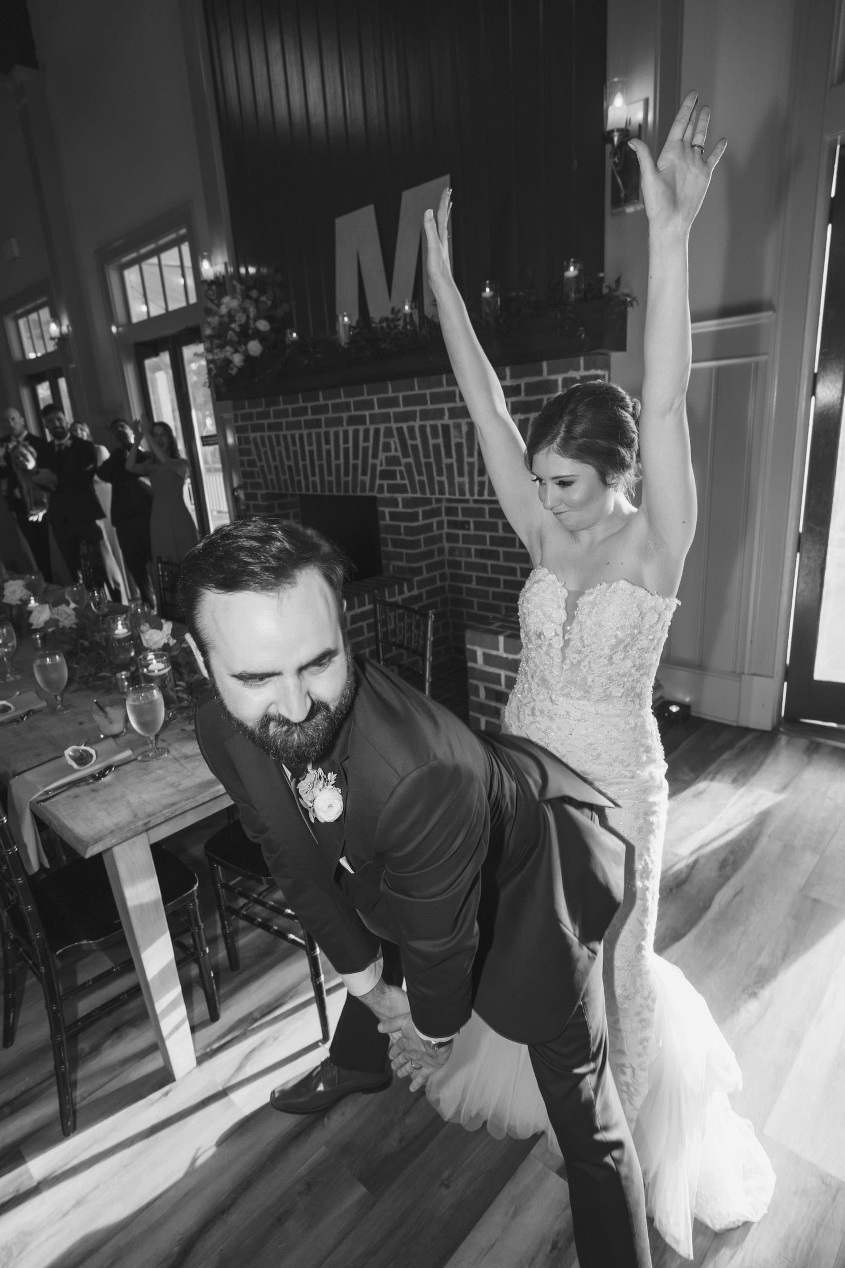 to have and to hold Black-and-white candid of a bride dancing behind her groom during their wedding reception inside Creek Club at I’On.
