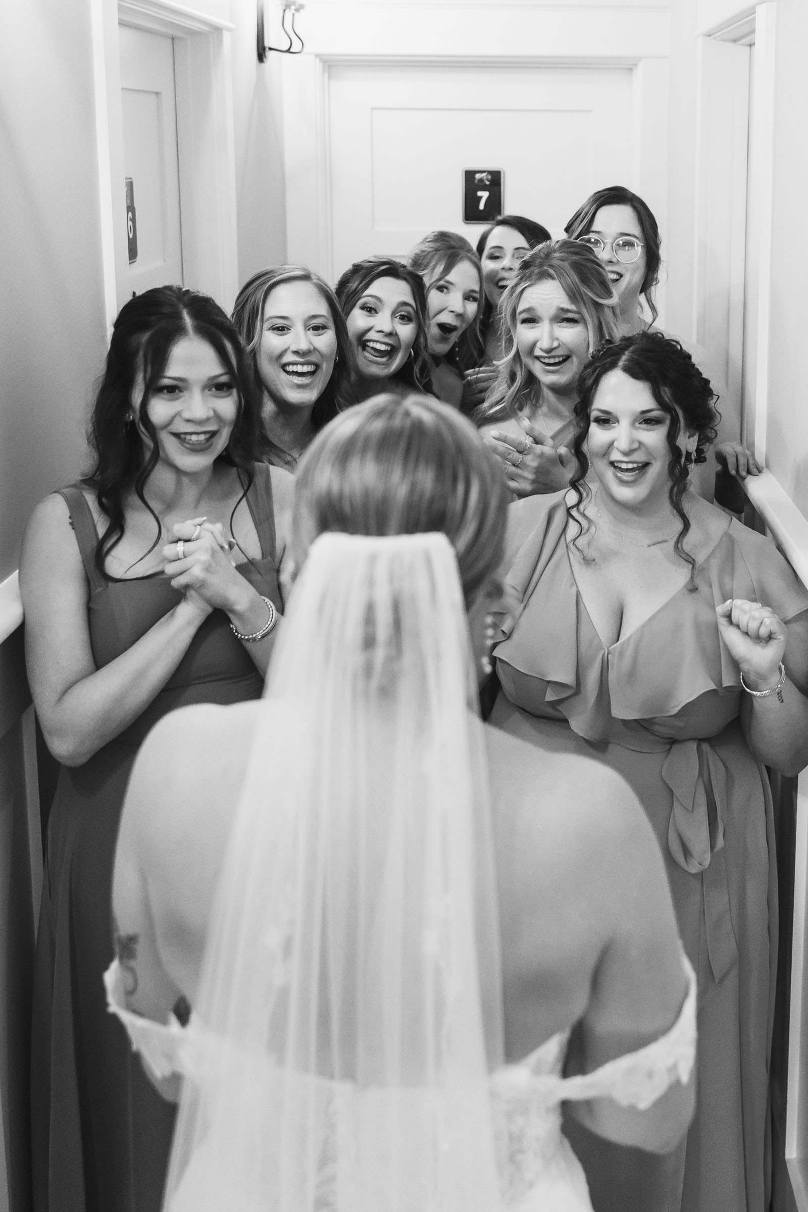 There She Is Black-and-white photograph of bridesmaids reacting excitedly as they see the bride dressed for her Creek Club at I’On wedding.