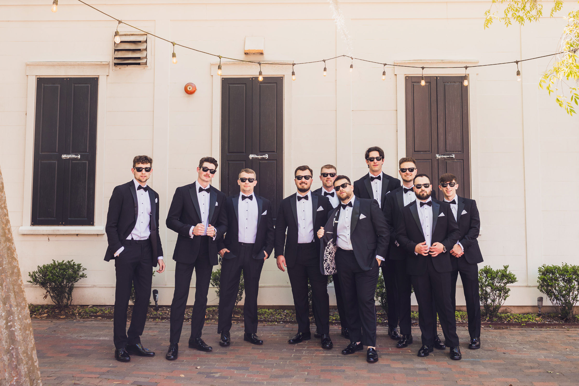 The Committee Groom and groomsmen in black tuxedos and sunglasses posing outside Creek Club at I’On before a Mount Pleasant wedding.