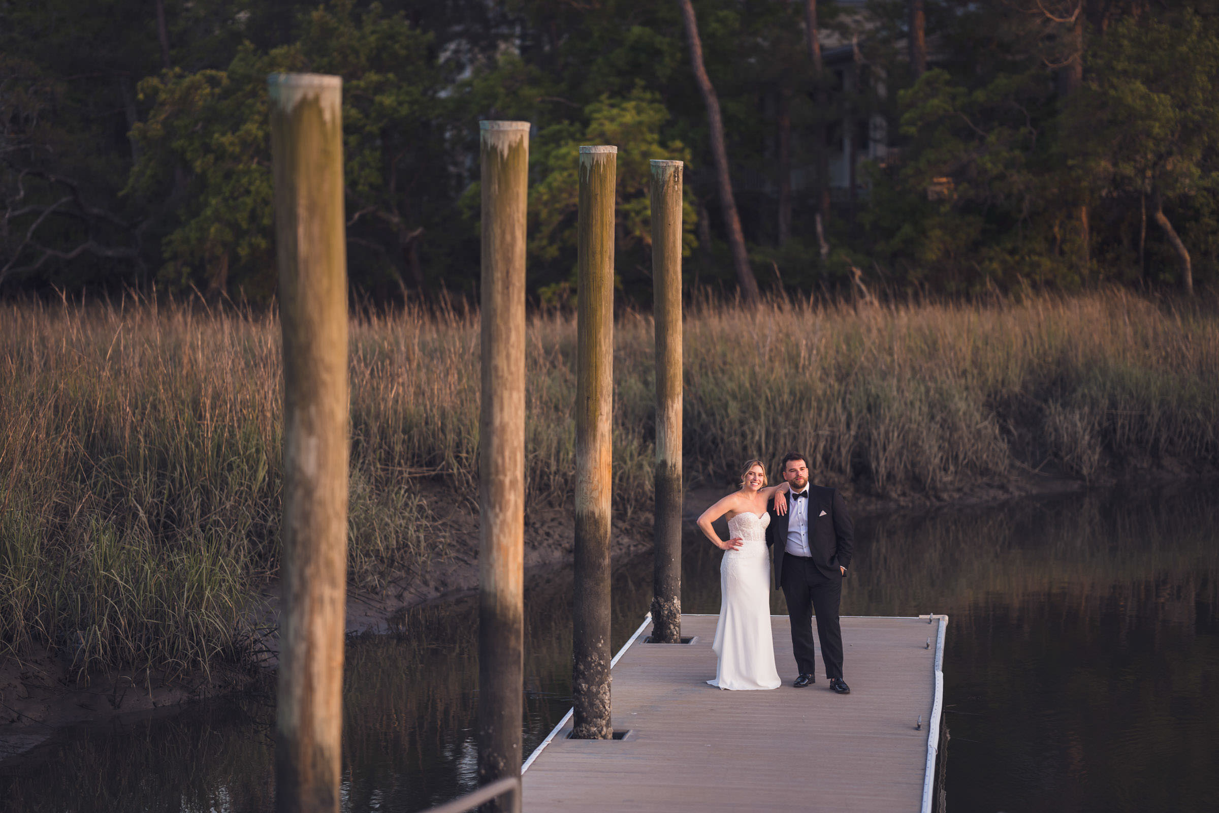 End of the Dock Bride and groom standing together at the end of the dock at Creek Club at I’On, surrounded by marsh grass and tidal creek.
