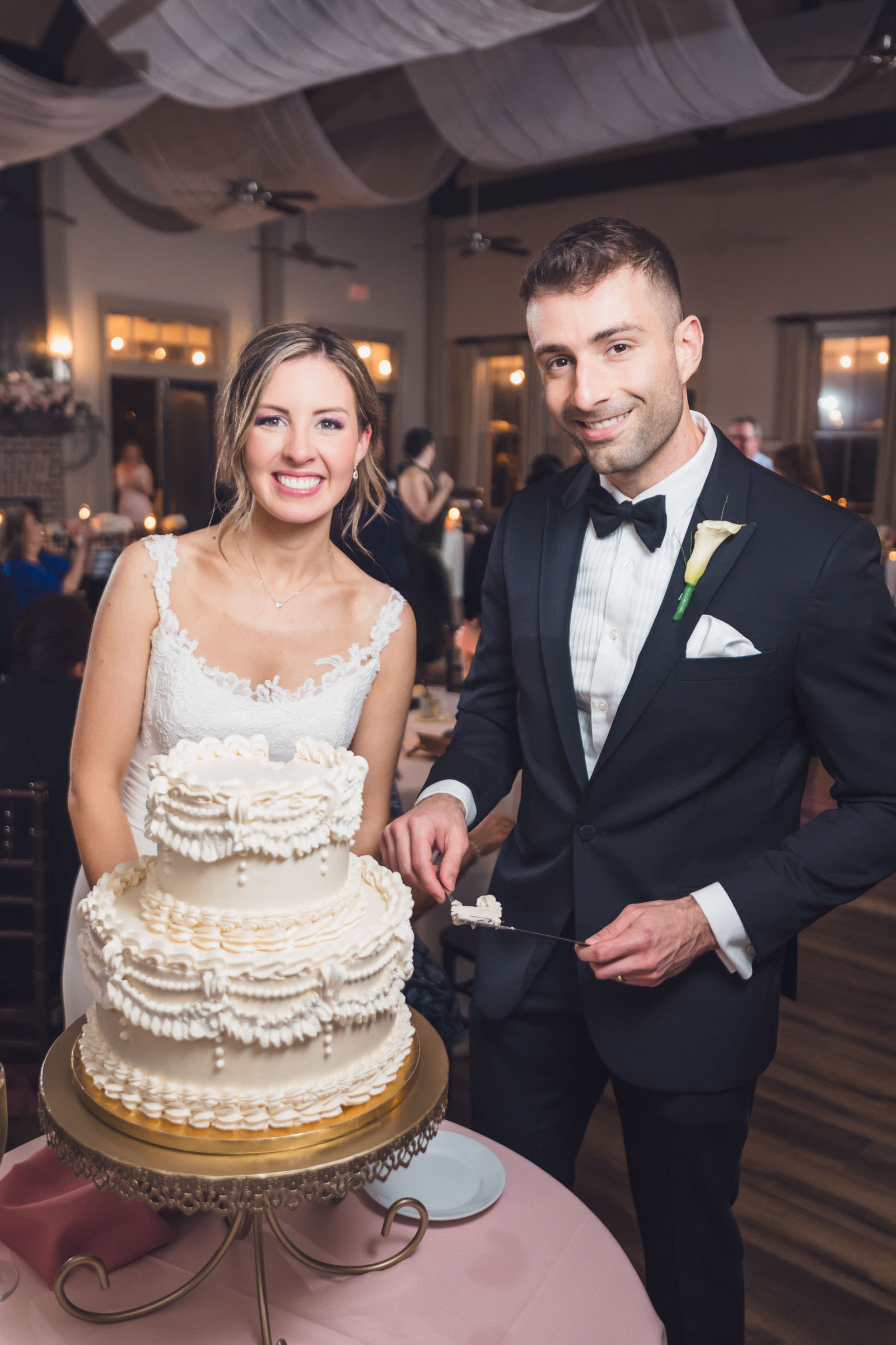 First Cake in Months. Bride and groom cutting a tiered wedding cake during their reception inside Creek Club at I’On.