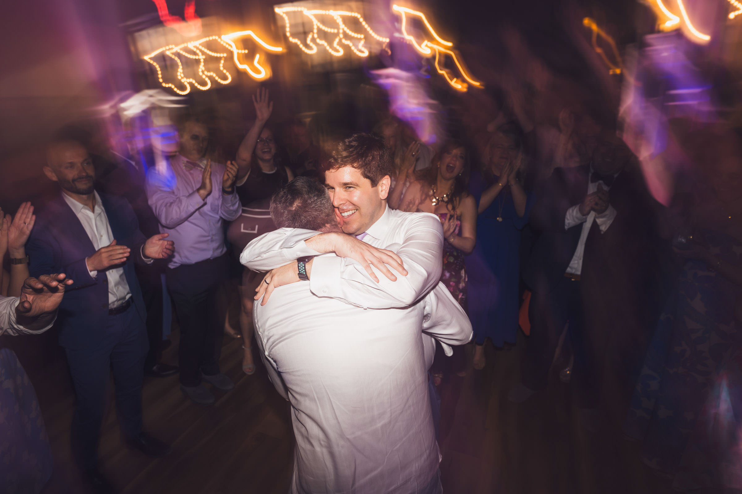 Found You Two grooms embracing on the dance floor during their evening wedding reception at Creek Club at I’On.
