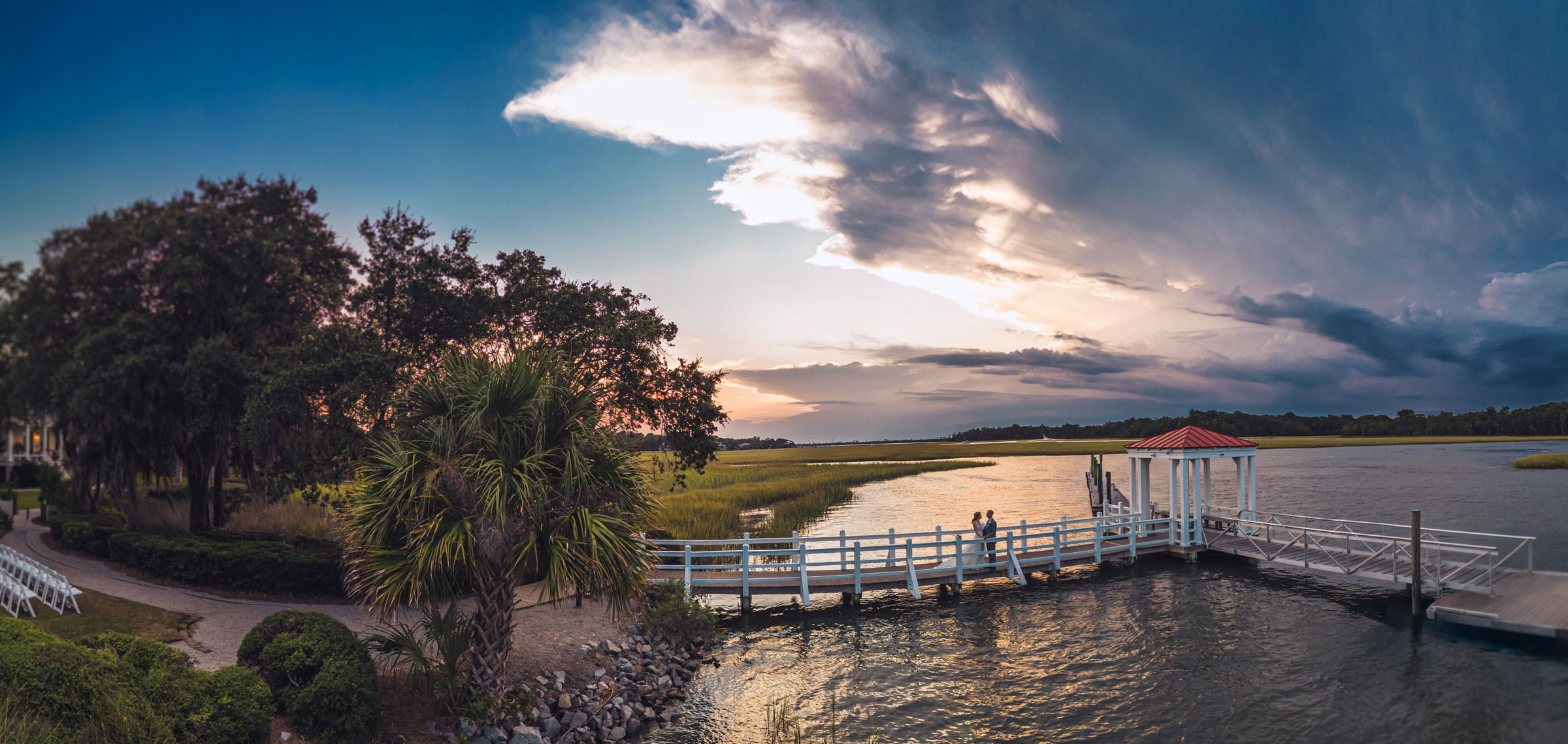 we show off sometimes Aerial sunset view of the dock, marsh, and tidal creek at Creek Club at I’On with a wedding couple standing near the water.