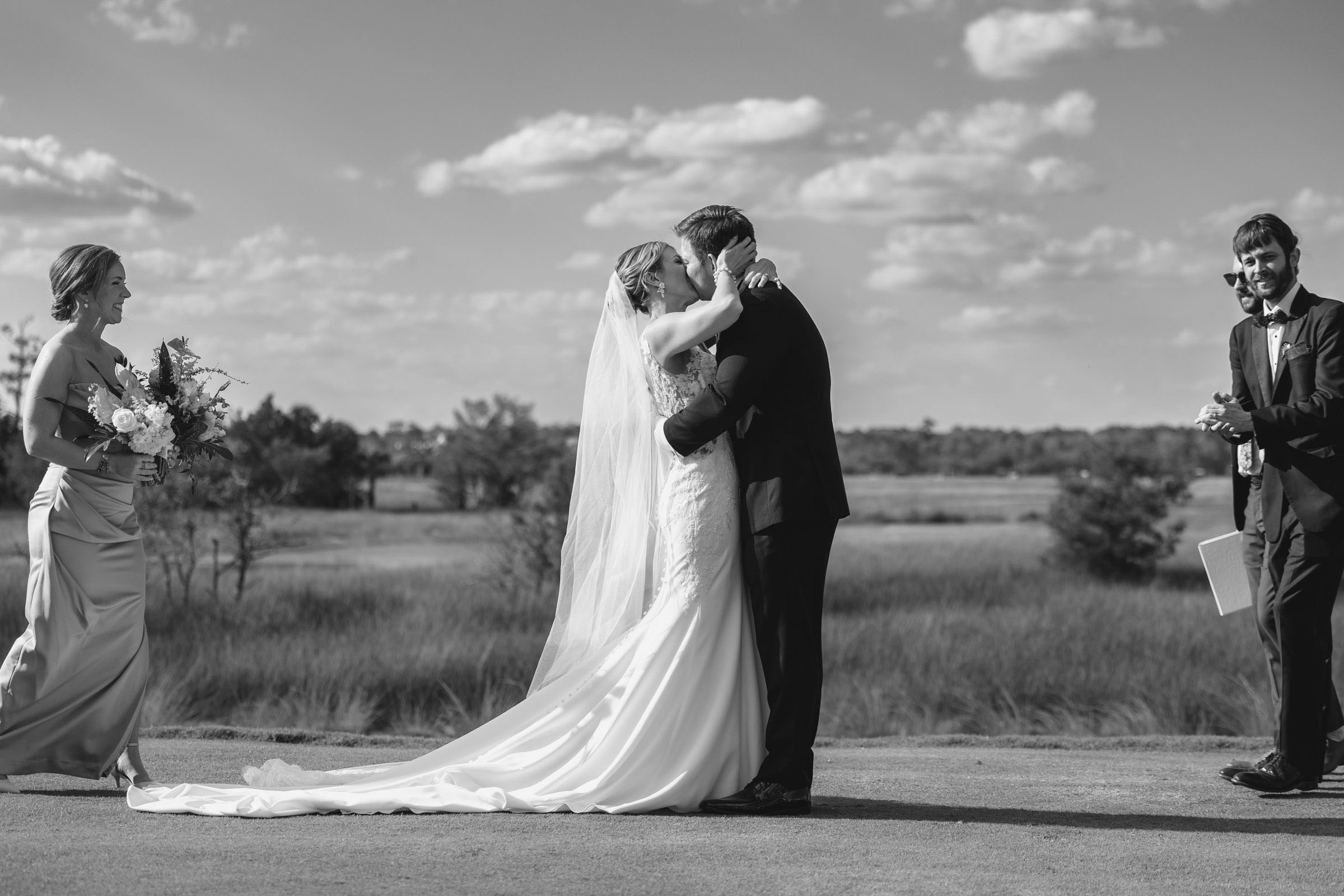 First Kiss Overlooking the Marsh Black-and-white photograph of newlyweds sharing their first kiss during a Daniel Island Club wedding ceremony overlooking the marsh.