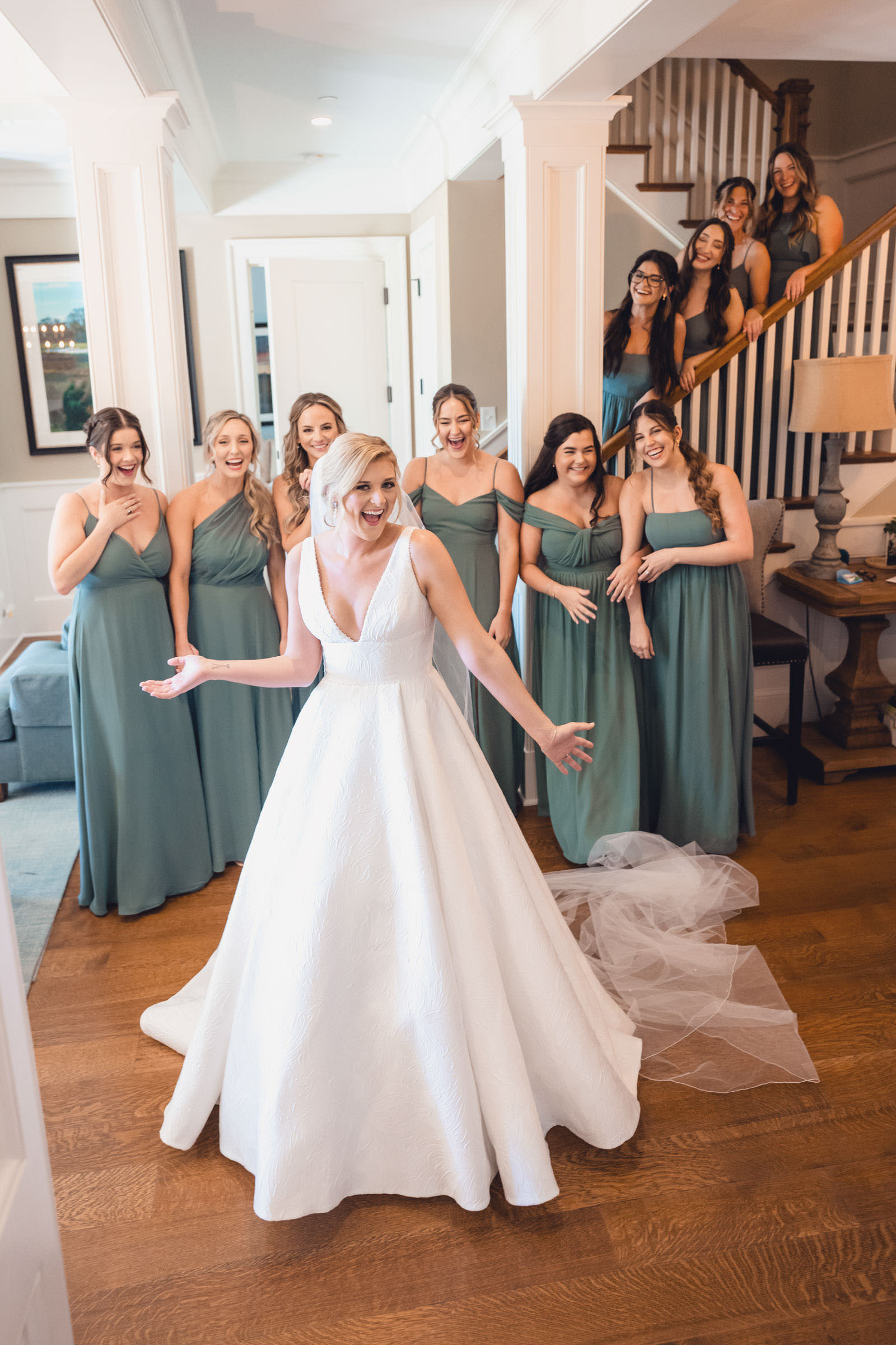 Bride and Bridesmaids Getting Ready Bride showing her wedding dress to laughing bridesmaids inside a Daniel Island Club cottage.