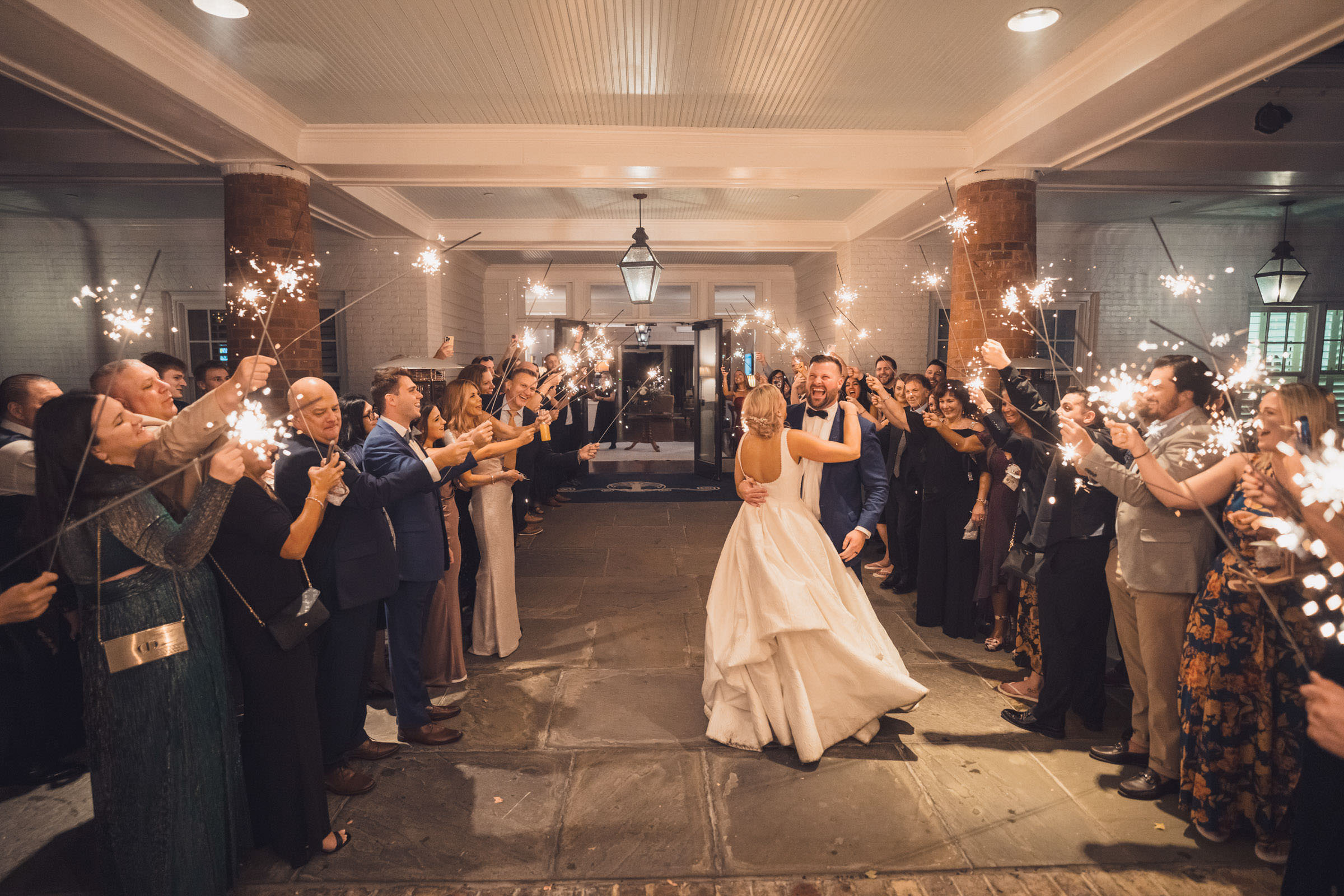 Sparkler Send-Off at Daniel Island Club Newlyweds walking through cheering wedding guests holding sparklers beneath the covered entrance at Daniel Island Club.