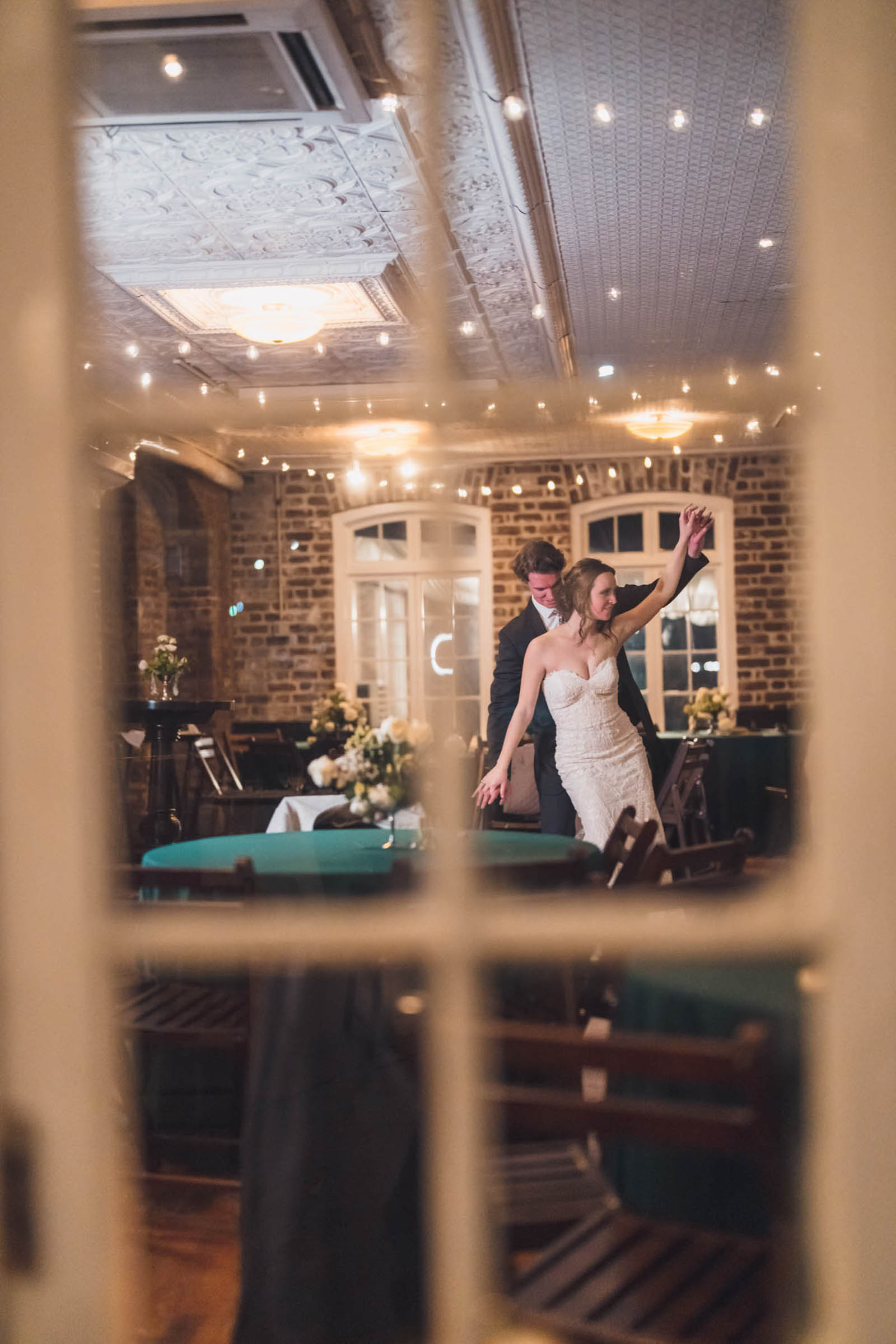 Dancing Inside the Historic Rice Mill Newlyweds dance together beneath cafe lights inside the brick reception room at the Historic Rice Mill.