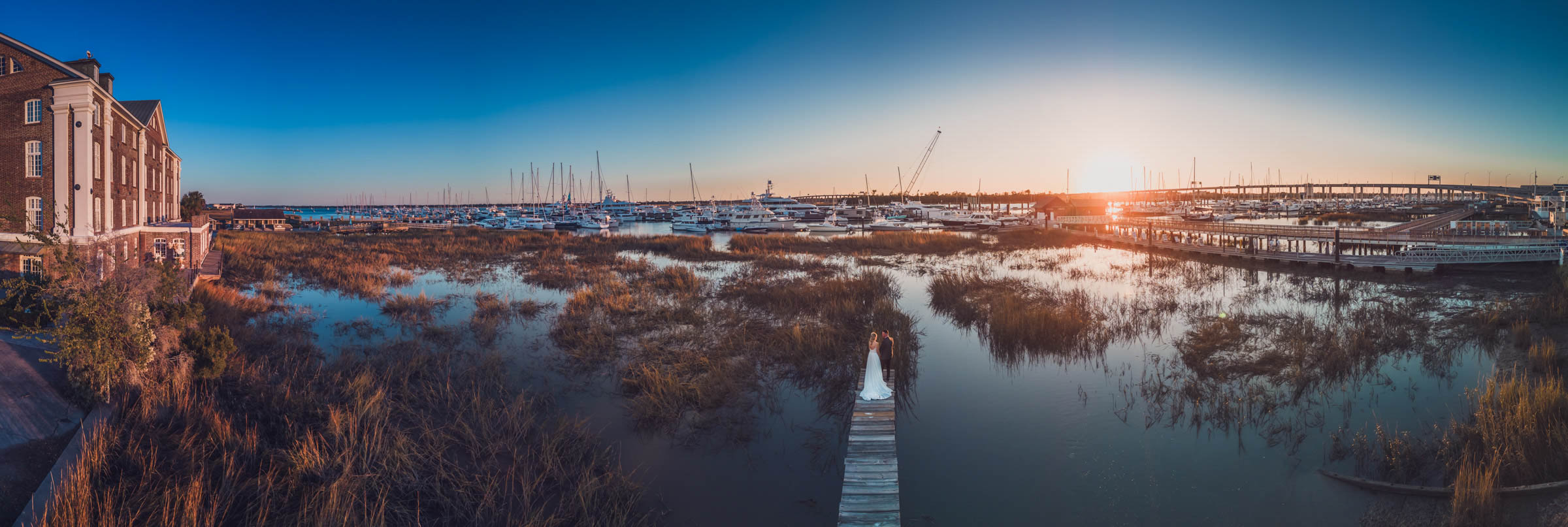 Historic Rice Mill Sunset Aerial Wide aerial panorama of newlyweds on the marsh dock beside the Historic Rice Mill and Charleston City Marina at sunset.