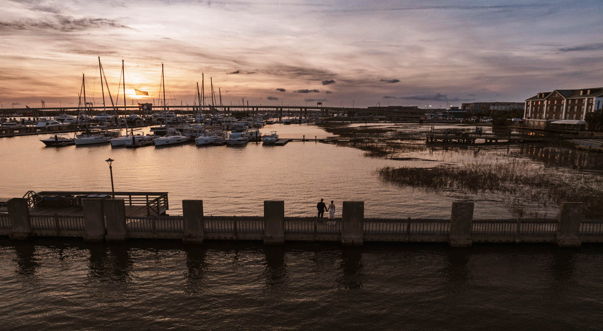 Historic Rice Mill Marina Sunset Newlyweds stand along the waterfront as the sun sets over sailboats at Charleston City Marina beside the Historic Rice Mill.