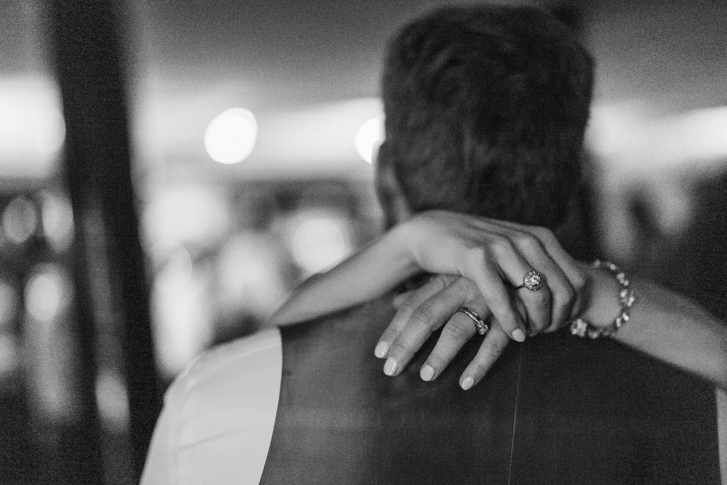 Wedding Rings at the Historic Rice Mill Black-and-white close-up of a bride's wedding and engagement rings as she embraces her partner during the reception.