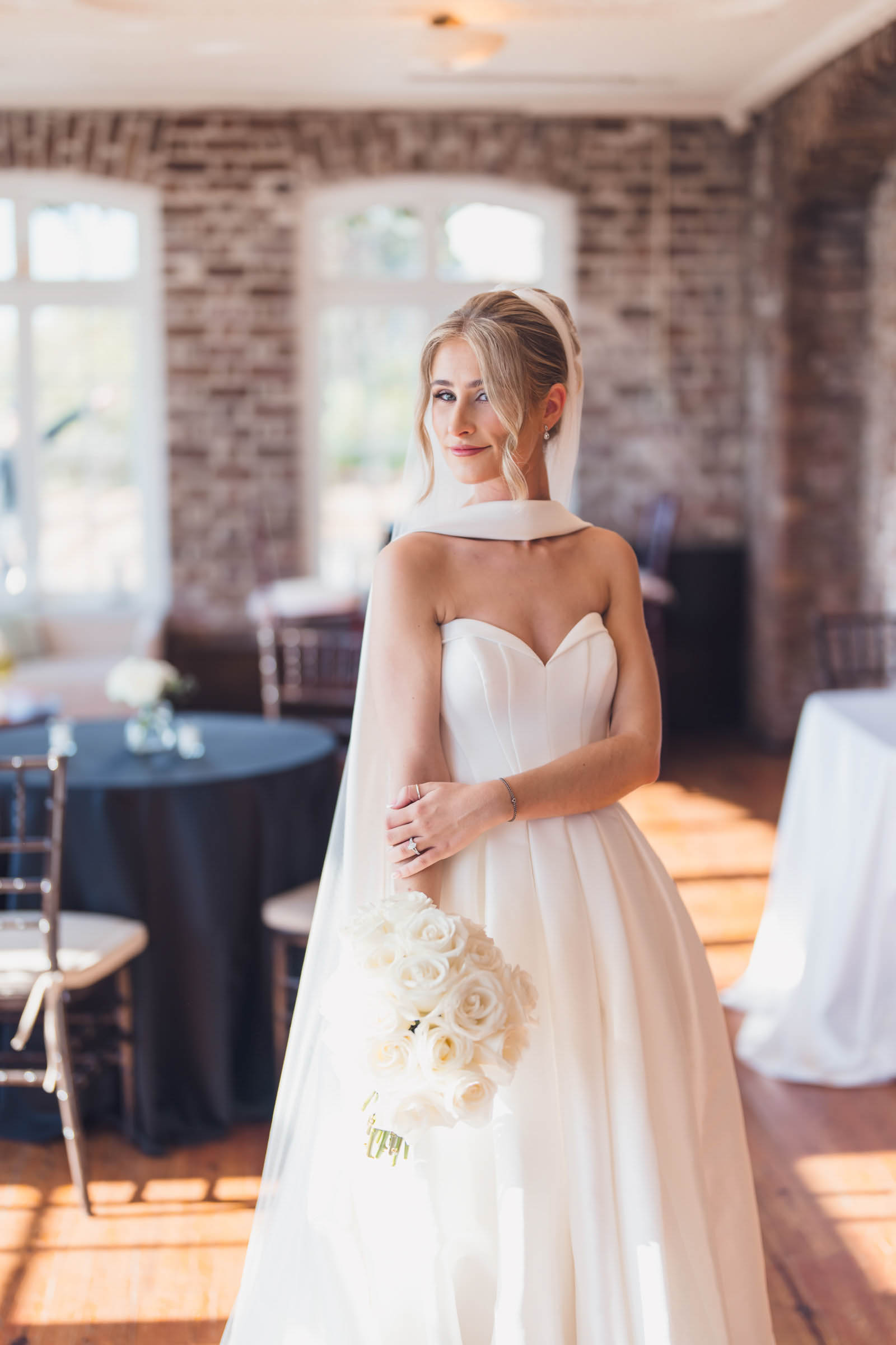 Historic Rice Mill Bridal Portrait Bride holds a bouquet of white roses for a sunlit portrait inside the Historic Rice Mill reception room.