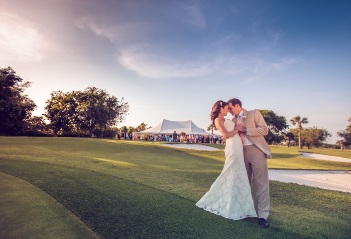 Groom dips bride with tent in the bg