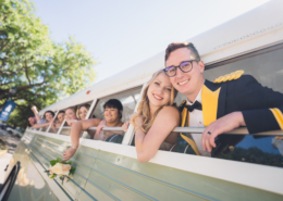 Bride and Groom and Wedding Party Leaning out of Vintage Bus after Wedding