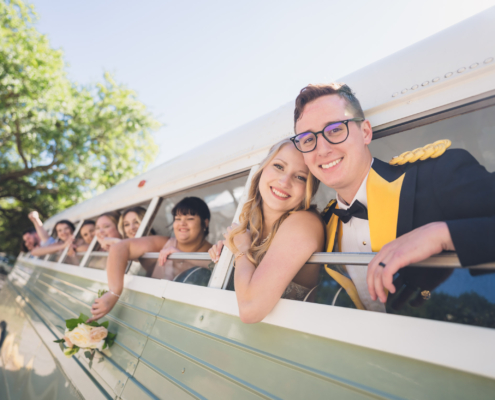 Bride and Groom and Wedding Party Leaning out of Vintage Bus after Wedding