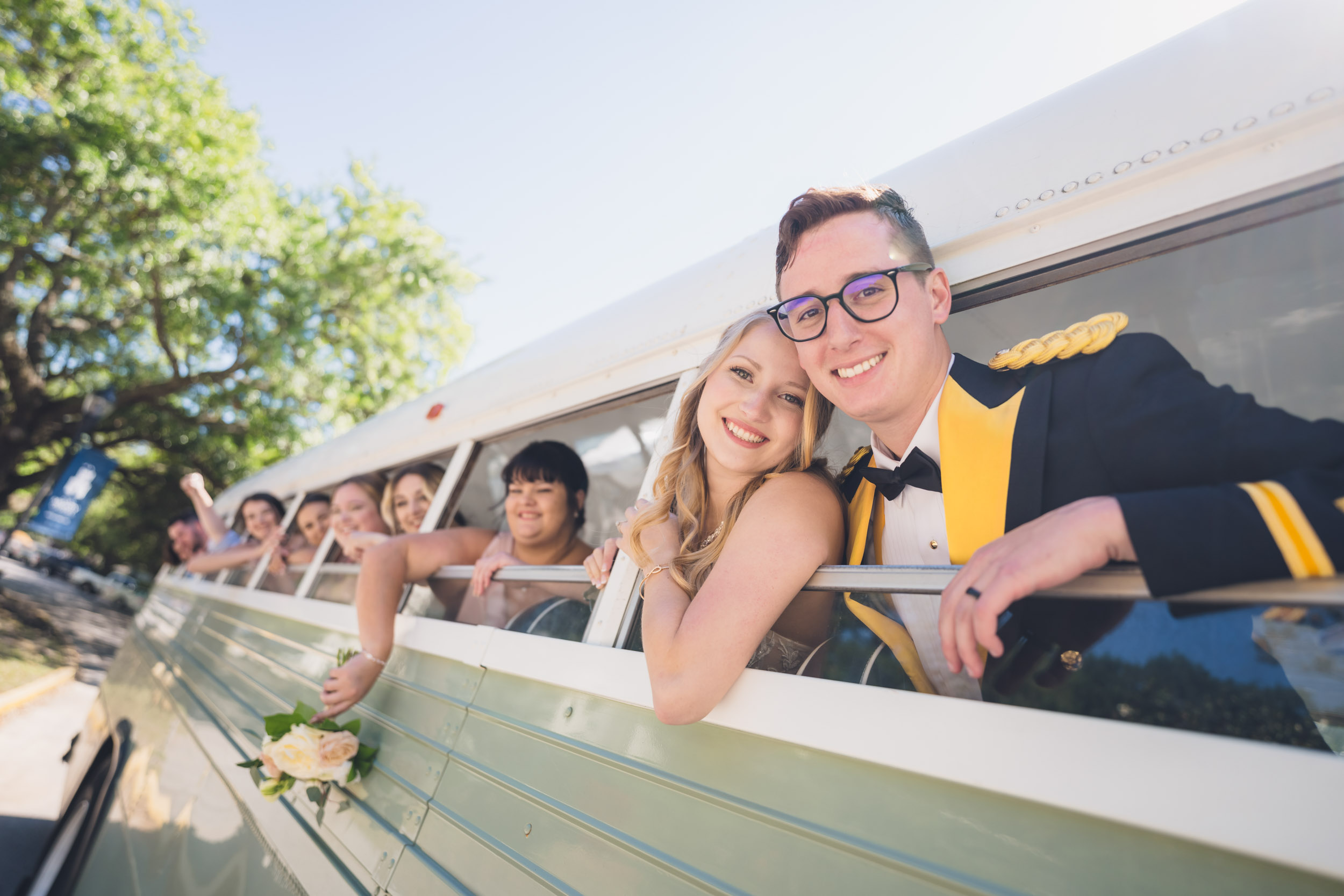 Bride and Groom and Wedding Party Leaning out of Vintage Bus after Wedding