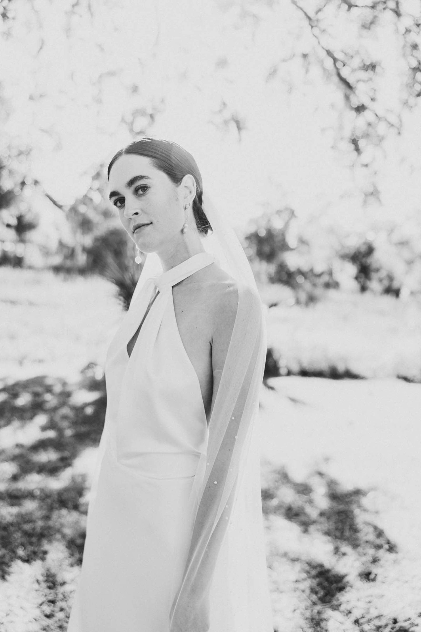 Bride portrait outdoors in soft light with veil draped over her shoulders—elegant black and white Charleston bridal portrait.