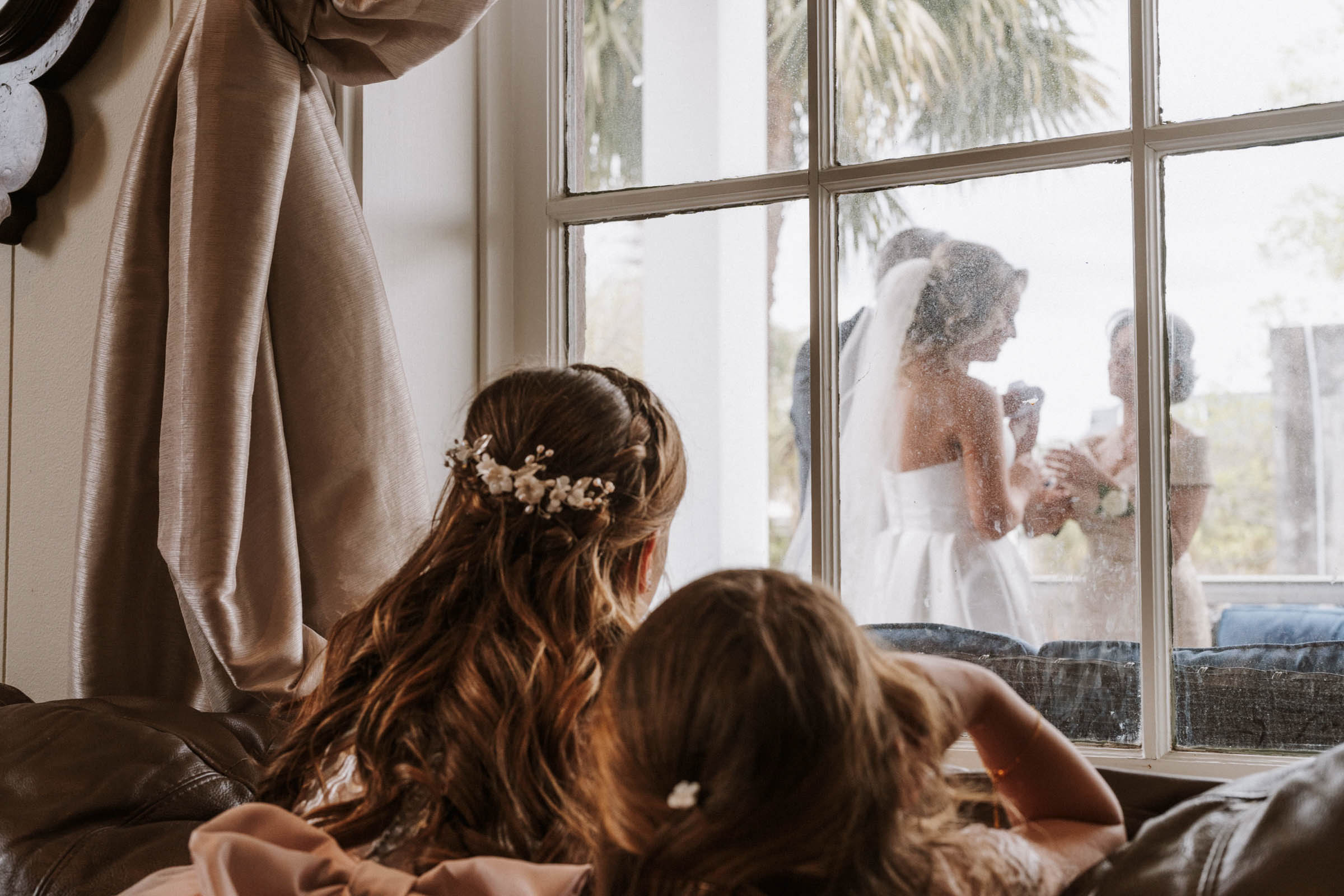 Flowergirl watching the bride and her parents through the window