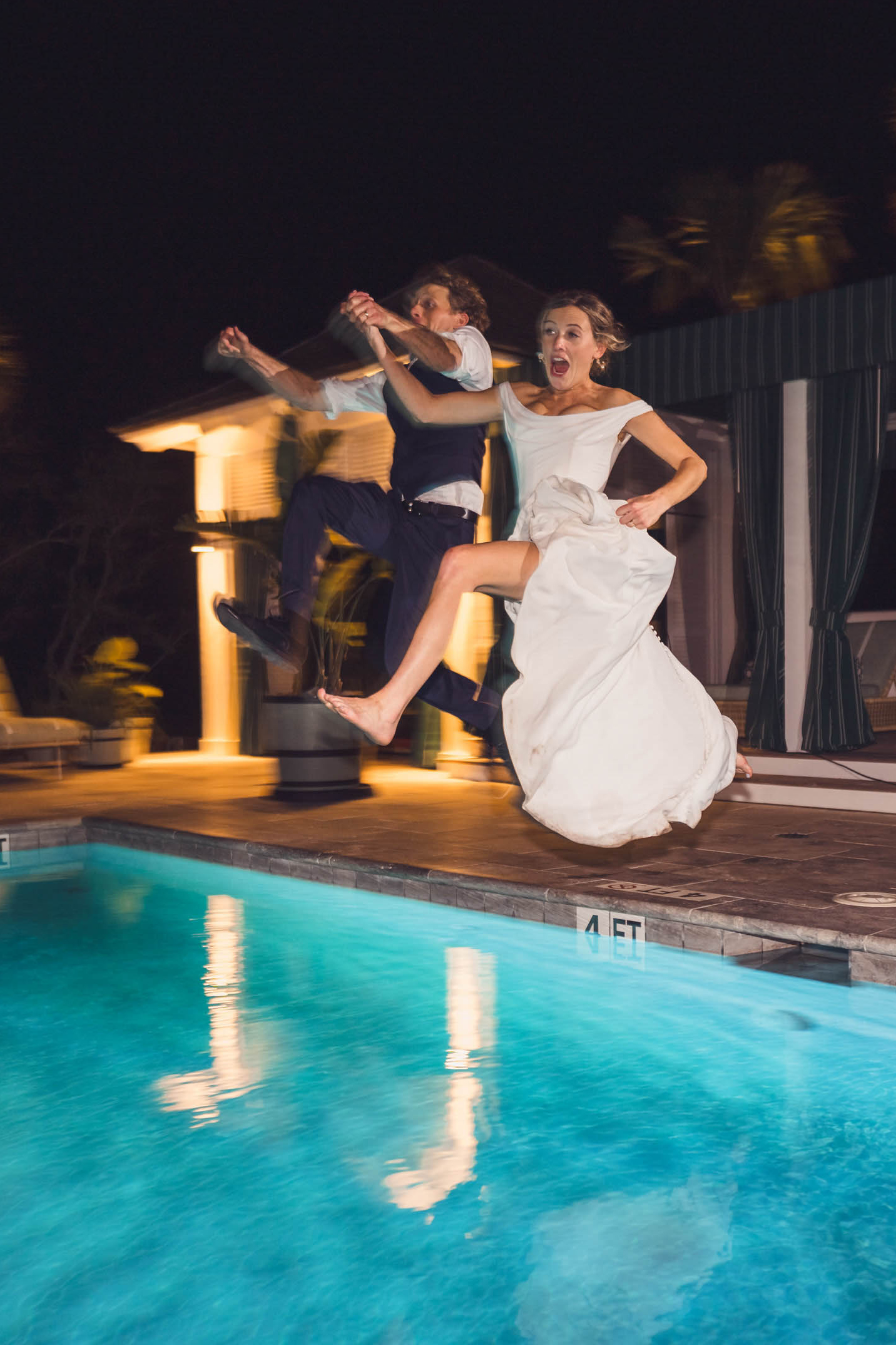 Bride and groom jumping into the pool at night after the reception at Dunland - Kiawah River in Charleston, South Carolina.