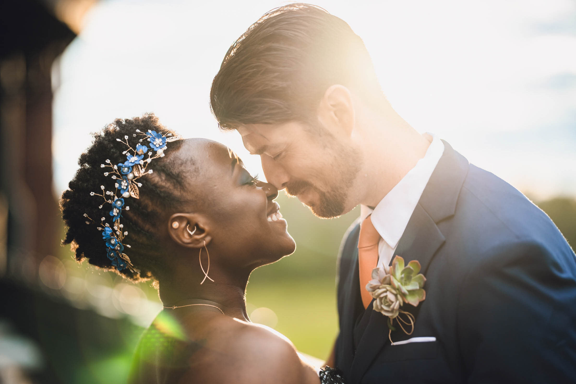 A couple touches noses in brilliant sunlight.