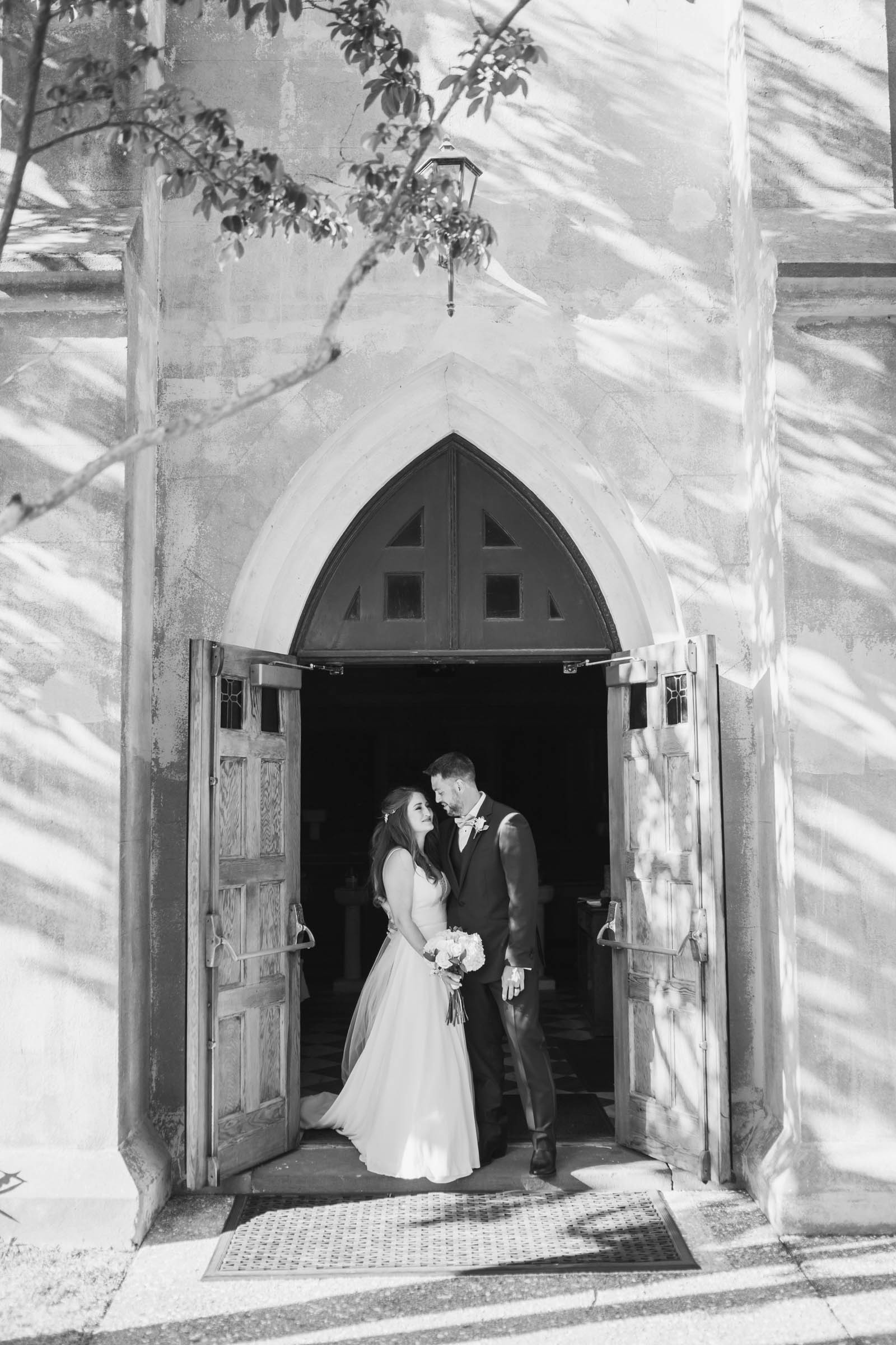 Bride and groom stand framed by the church doorway at Stella Maris on Sullivan’s Island near Charleston, South Carolina.