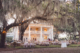 Wide view of outdoor wedding reception at Admiral’s House with string lights and oak trees